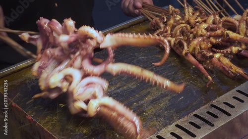 Street vendor is frying octopus satay at a food market