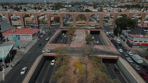 Aerial perspective of iconic stone arches defining Querétaro's historic district with gentle traffic flow and preserved colonial structures creating urban landscape