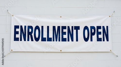 Enrollment open sign displayed on a white brick wall for educational registration and academic admission announcements in a professional school setting