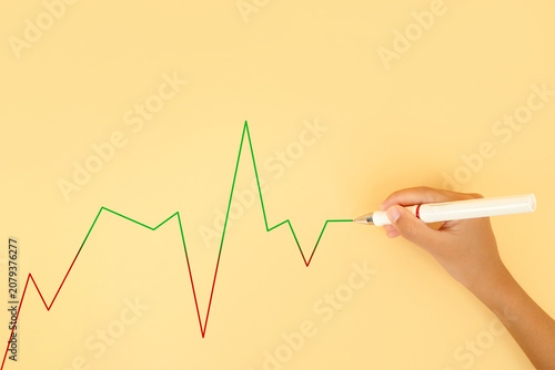 Hand drawing a fluctuating line chart on a pastel background. Concept of market volatility, financial performance, business trends, investment risk and data analysis.