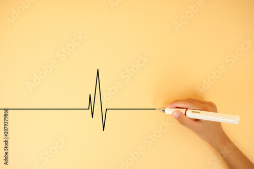 Hand drawing a heartbeat line on a pastel background. Concept of life, health monitoring, medical care, survival, emergency response and wellness awareness.