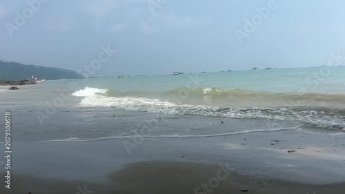 Close up of gentle ocean wave and white sea foam on a sandy beach