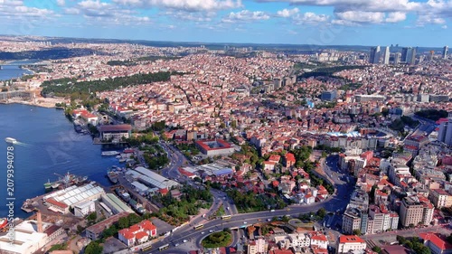 Aerial drone view of Beyoglu district rooftops, the Golden Horn waterfront, ferries, and Istanbul's European side cityscape extending to the horizon, Turkey, daytime.