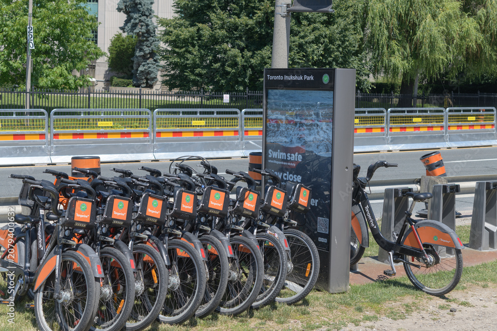 Obraz premium Tangerine Financial orange sponsor marketing on Bike Share rental vehicles near Toronto Inukshuk Park