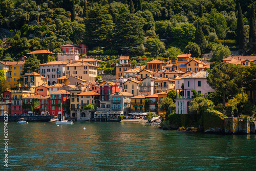 Colorful buildings along the lakeside in Varenna, Italy, with lush greenery and clear blue water reflecting the vibrant architecture
