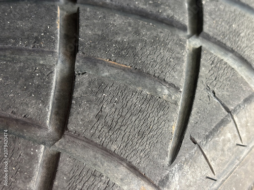 The tire tread is deteriorating and starting to show cracks on the surface