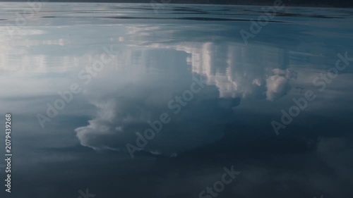 Glassy surface of the river with reflection of the cumulonimbus clouds