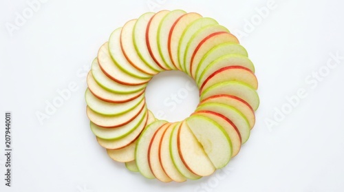 Fresh apple slices arranged in a circular wreath pattern on a clean surface for healthy food photography and diet menu