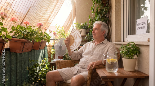 elderly person summer heat shade balcony senior hydration safety older person sits comfortably in shaded balcony with water nearby showing senior heat safety and calm cooling routine with distinct