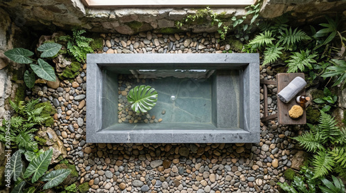 Enchanting Jungle Bath Oasis: A serene stone bathtub filled with clear water, nestled amidst lush green ferns and tropical plants, inviting a tranquil escape into nature's embrace.