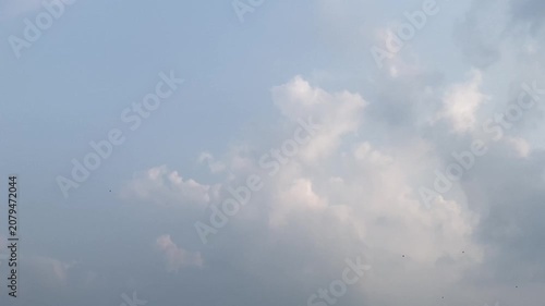 Beautiful cloudscape with soft white clouds moving across a serene blue sky with distant birds