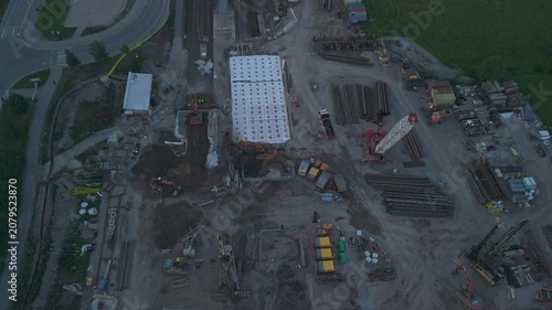 wide aerial drone view of a construction site with tower cranes excavators and concrete foundations surrounded by forest highlighting early stage infrastructure development
