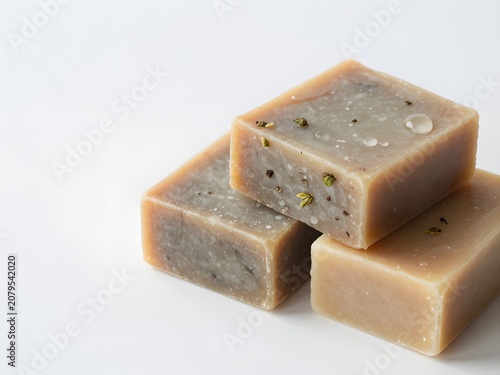 Natural Handmade Soap Bars: Three meticulously crafted, natural soap bars with visible botanical inclusions and subtle textures are artfully arranged, hinting at purity and gentle cleansing.
