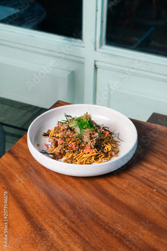 Savory Noodle Delight: A visually appealing bowl of delicious noodles, artfully arranged with savory toppings and fresh herbs, presented on a rustic wooden table.