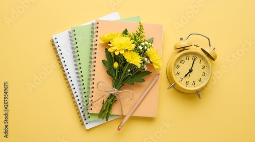 Teacher day celebration with colorful notebooks flowers and alarm clock