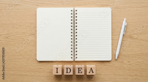 Open notebook with a pen and wooden blocks spelling the word idea on a simple flat surface for creative planning and business strategy