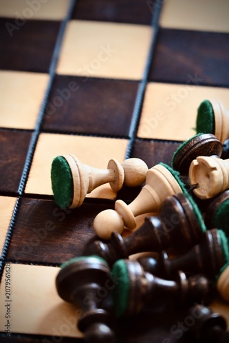 фотографія Vertical close-up of scattered wooden chess pieces piled in chaos on a chessboar