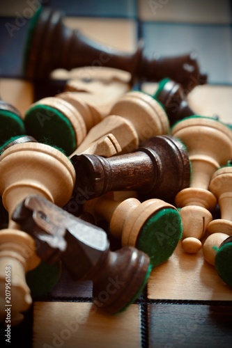 Принти на полотні Vertical close-up of scattered wooden chess pieces piled in chaos on a chessboar