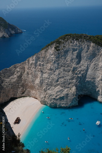 Cuadro en lienzo Vertical view of Navagio (Shipwreck) Beach in Zakynthos, Greece, showcasing towering white limestone cliffs above crystal-clear turquoise water from the iconic cliff viewpoint