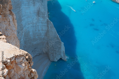 фотографія Hidden beach below the Navagio Beach viewpoint in Zakynthos, Greece, featuring crystal-clear turquoise water, dramatic white limestone cliffs, and an untouched Mediterranean coastline