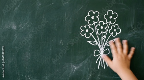 Hand drawing flowers on chalkboard for teacher day celebration