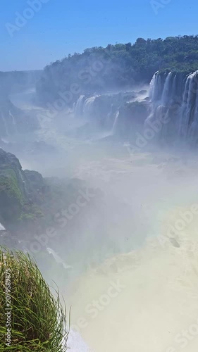 Powerful water cascades down lush green cliffs at iguazu falls. A majestic view of the garganta del diablo, creating a dense mist