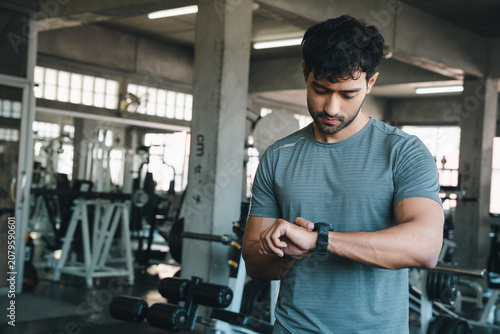 Photos Man gym watch fitness exercise athlete checking wearable device in industrial tr