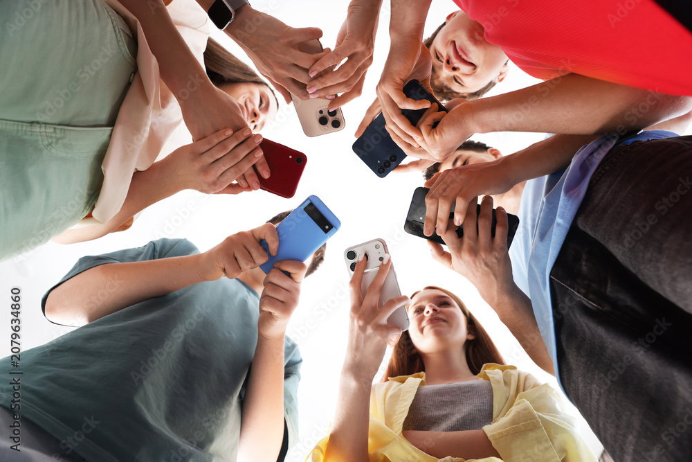 Obraz premium Group of teenagers with different smartphones indoors, bottom view