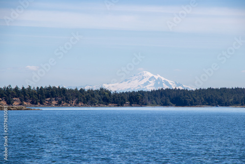 Distant snow capped mountain over serene coastal waters