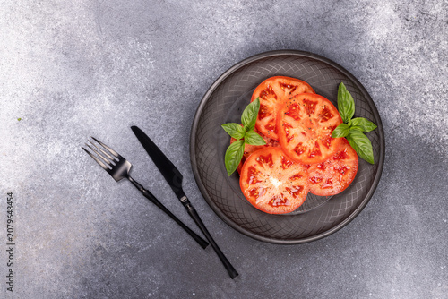 Fresh sliced tomatoes with basil on plate, healthy food