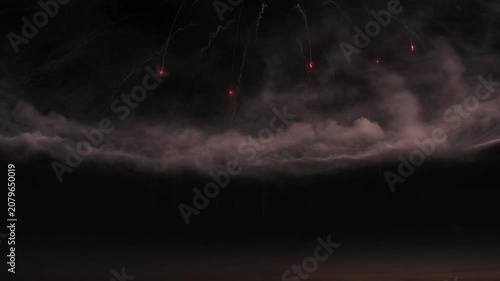Fiery streaks descend through smoky, dramatic clouds at dusk.