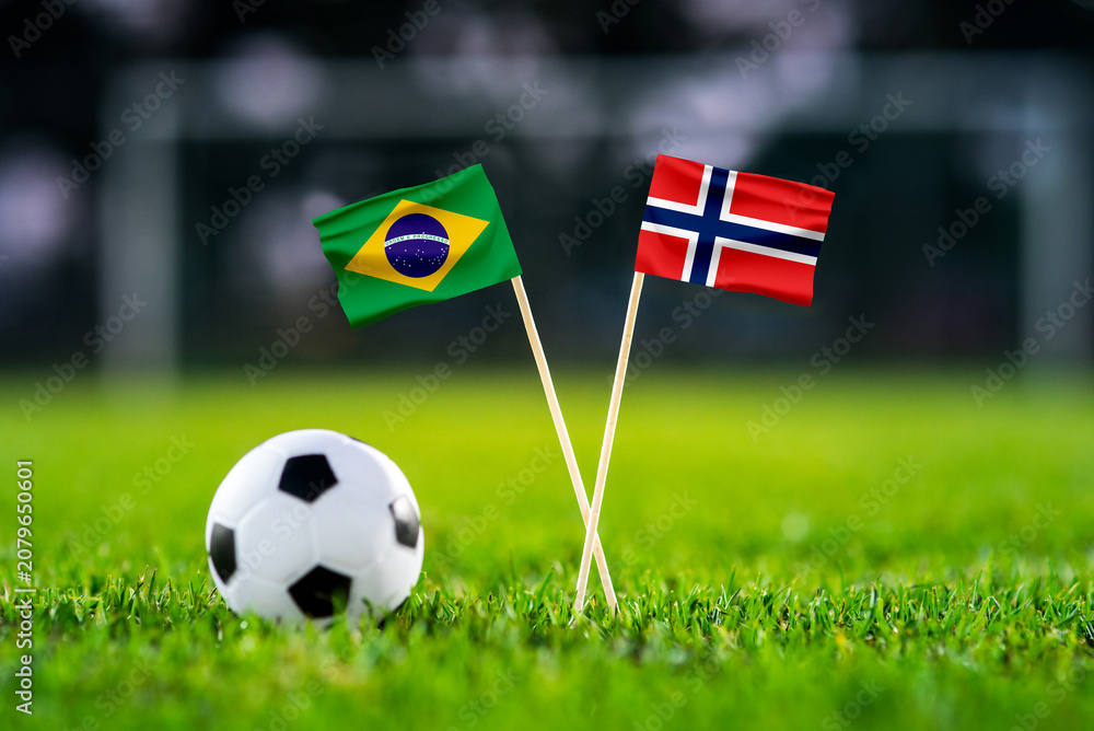 Obraz premium Brazil vs Norway, national flags before international football tournament Round of 16 match, football on green grass with stadium in the background, East Rutherford, New Jersey, USA, July 5, 2026