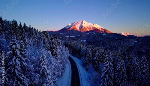 beautiful winter road with dark night road through forest and mountains, wintery scene at sunset