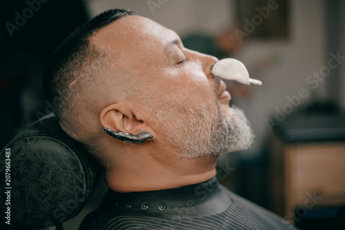 Fotografía Caucasian male mature grooming experience in modern barbershop, ear and nose hai