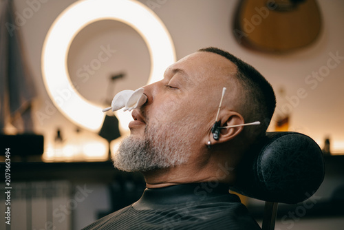 Fotografie Male client in barbershop with relaxing treatment, ear and nose hair removal wax