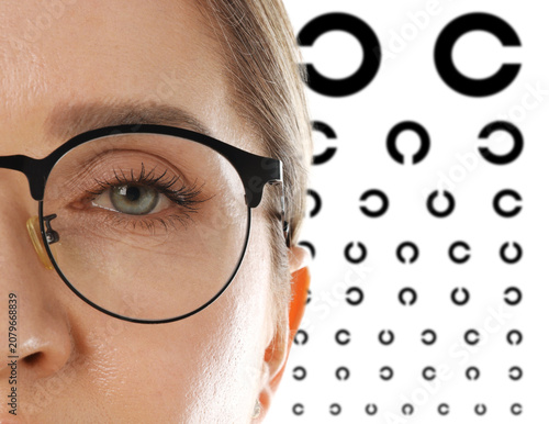 Slika na platnu Woman in glasses and eye chart on white background, selective focus