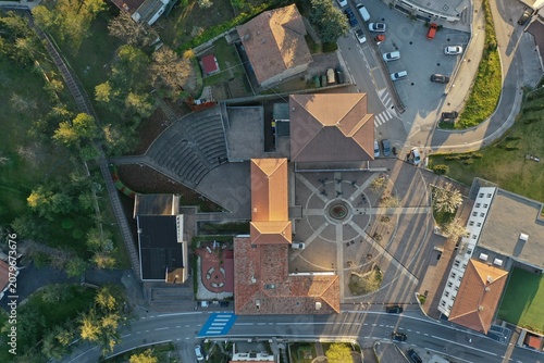 Aerial view of the town square featuring a circular paved plaza, terracotta-tiled rooftops, and an amphitheater area in Chiesanuova, Chiesanuova, San Marino.