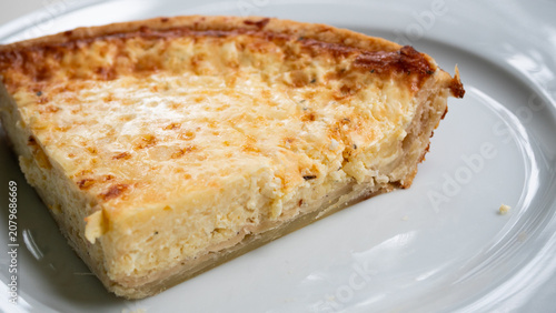 One slice of the Swedish delicacy Västerbottenpie on a white plate. A cheese pie typically served on holidays and special occasions, containing the key ingredient Västerbotten cheese. This cheese can