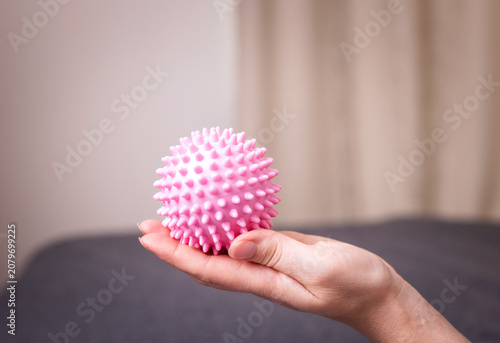 Schilderij op canvas Hand holding a pink spiky ball, close-up of a textured toy, simple object portra