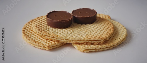 Chocolate candies on top of round crackers against a white background