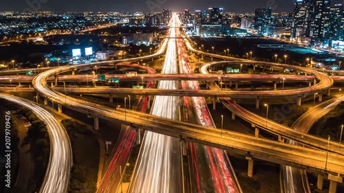 Aerial view of complex highway interchange with car light trails at night in a modern city