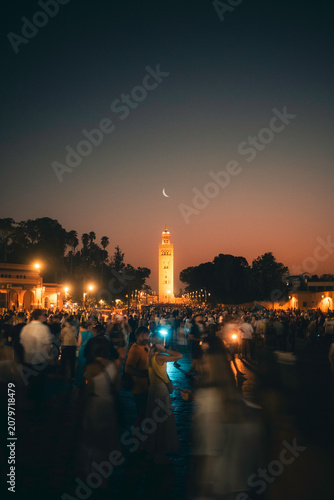 Crowded Marrakech Square at Dusk With Illuminated Minaret