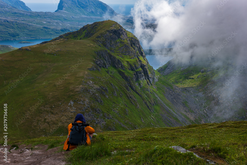 Fototapeta premium Hiker with Orange Backpack Exploring Lofoten Mountains Norway