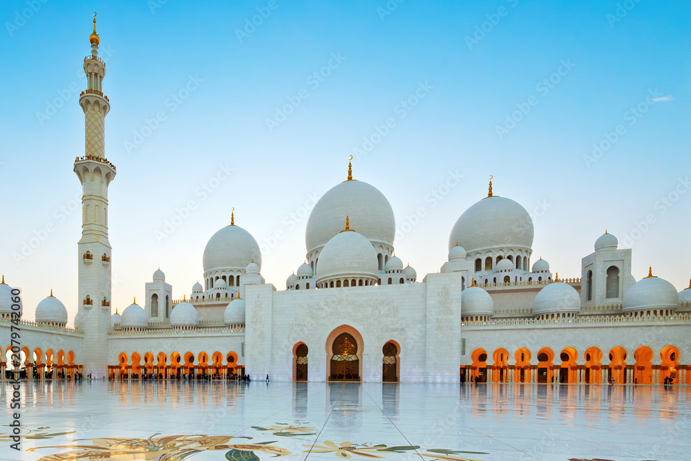Fototapeta premium Interior courtyard of the white marble Sheikh Zayed Grand Mosque, the largest mosque in the UAE, illuminated at twilight in Abu Dhabi, United Arab Emirates.