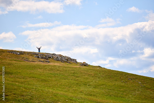 Obraz na plátne Lonely figure stands atop grassy hill