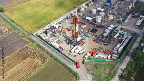 Oil and gas a land rig, onshore drilling rig, in the middle of a rice field aerial view from a drone