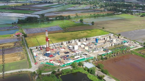 Oil and gas a land rig, onshore drilling rig, in the middle of a rice field aerial view from a drone