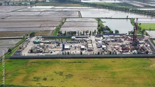 Oil and gas a land rig, onshore drilling rig, in the middle of a rice field aerial view from a drone