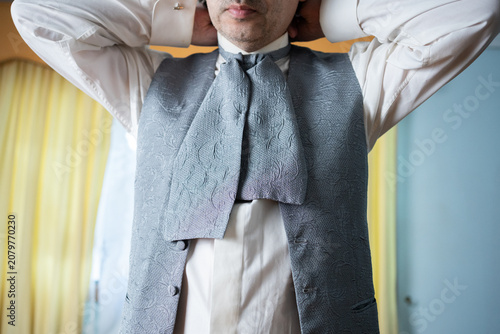 Canvastavla Unrecognizable groom fastening his traditional silver cravat tie around high col
