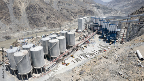 Fotografie Aerial view of a pozzolan plant with storage silos, pipe racks, processing facilities, and support infrastructure supplying cementitious materials for a large dam construction project